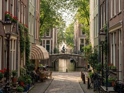 Cyclist crossing a small bridge over an ivy-lined canal in the historic centre of Amsterdam, Netherlands