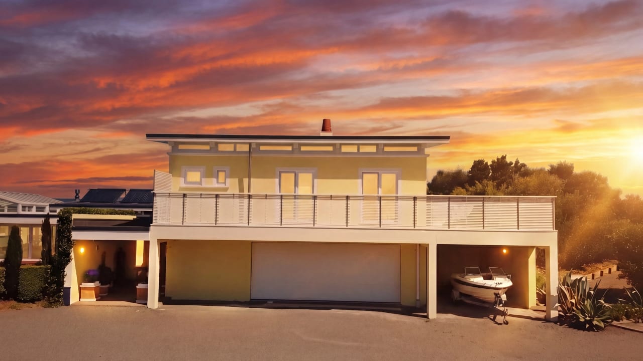 Guest house above double garage at golden sunset, boat stored in right bay, wrap-around deck, Hawke's Bay coastal property