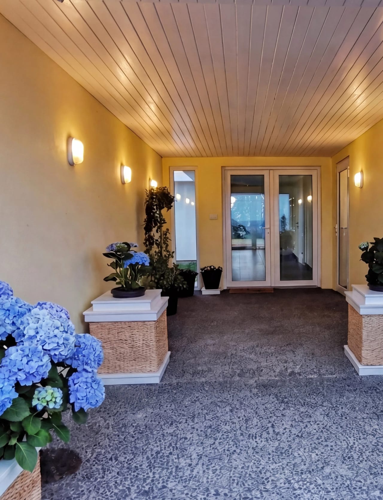 Sheltered entrance at Bay House showing the main house double doors ahead and the guest house staircase to the right, surrounded by coastal planting, Hawke's Bay, New Zealand.