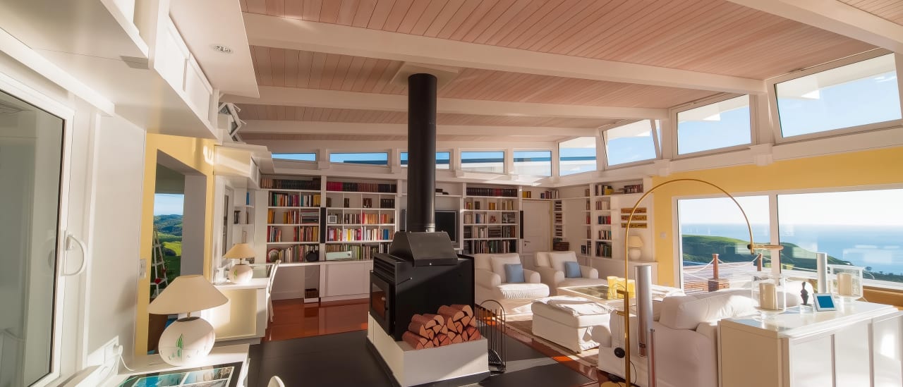 Panoramic lounge with library wall, freestanding fireplace, T&G pine ceiling and Hawke's Bay coastal views in this luxury home for sale.