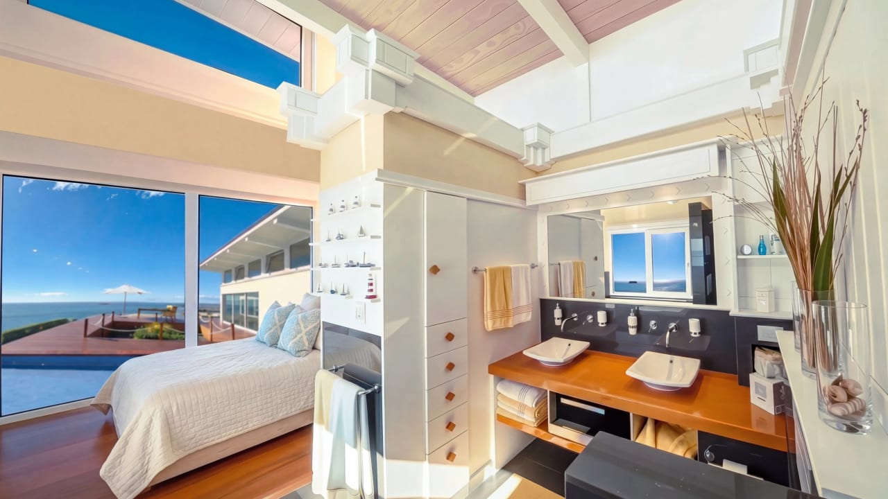 Luxury homes for sale- like this seaview bedroom at Bay House with private deck overlooking the illuminated water feature and Pacific Ocean at sunrise, Hawke's Bay, New Zealand.