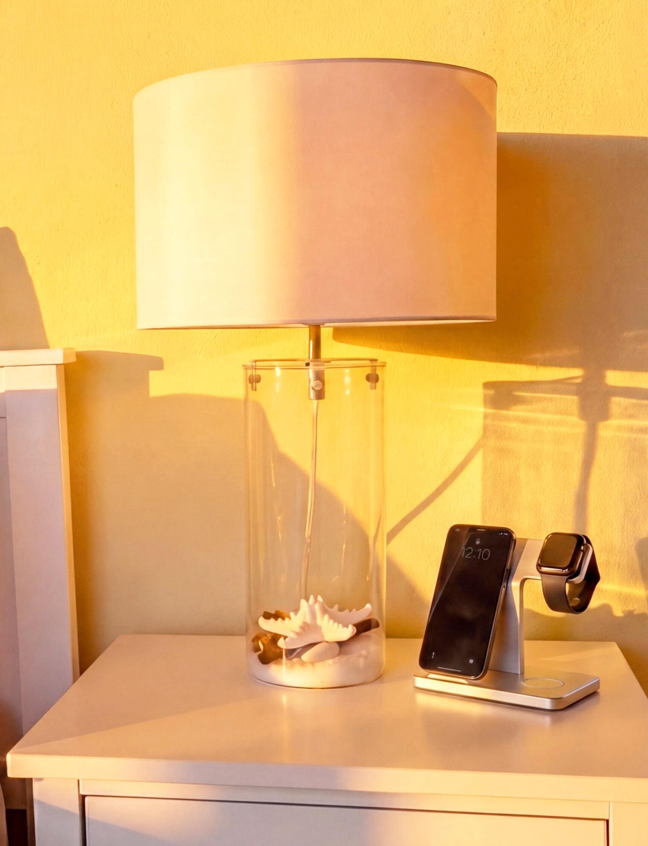 Hawkes Bay turnkey coastal home bedside lamp close-up — clear cylinder with shells and Apple MagSafe charging dock