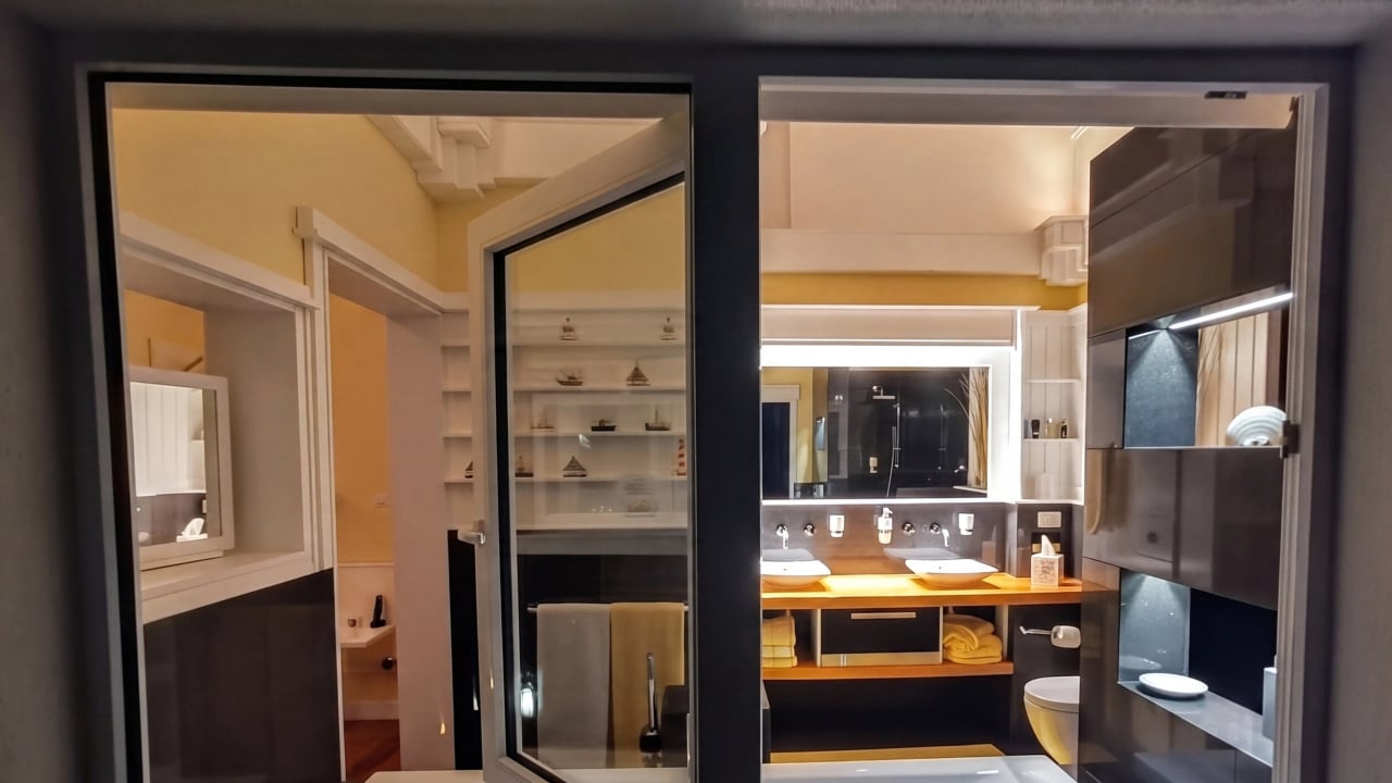 Bay House Seaview ensuite at night — seen through Koemmerling glass, warm interior light, double vanity beyond