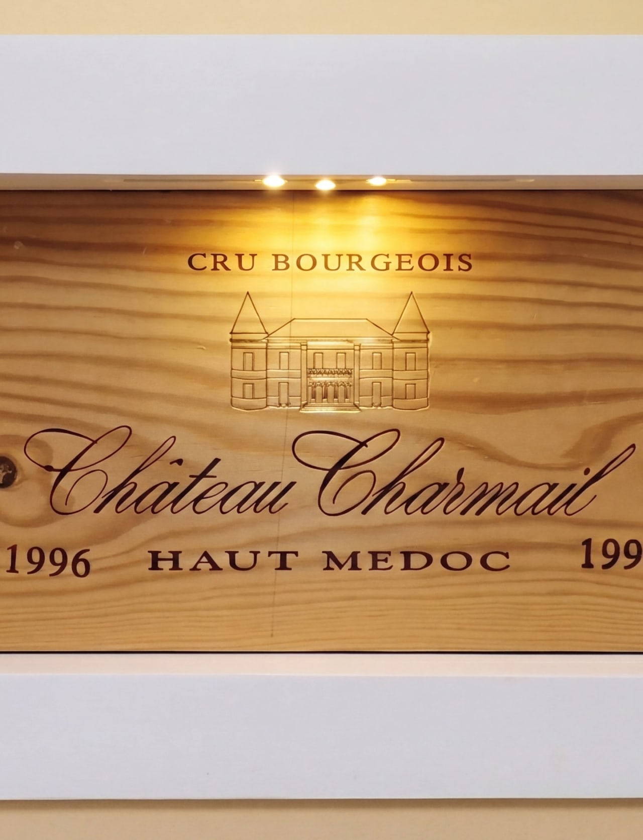 Portrait view of Bay House wine niche showing Château Charmail 1996 Haut Médoc case with natural window light above and uplighting within.