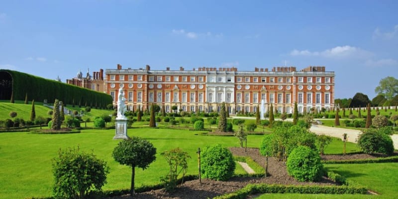Exterior View Of The Historic Kensington Royal Palace, With Its Manicured Gardens Stretching Out In The Foreground.