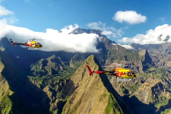Deux hélicoptères jaune et rouge survolent les pics du cirque de Mafate à La Réunion
