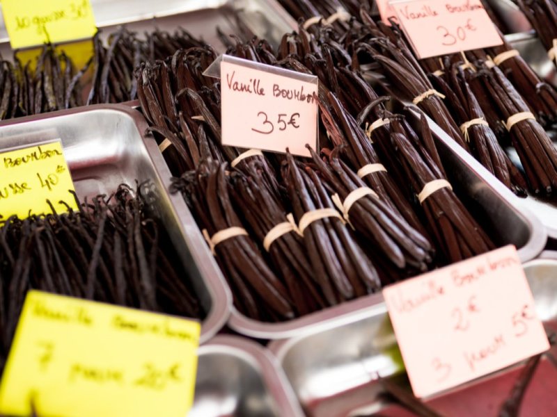 Bottes de gousses de vanille noires dans des bacs métalliques, étiquettes manuscrites « Vanille Bourbon » à 35 € et 30 €