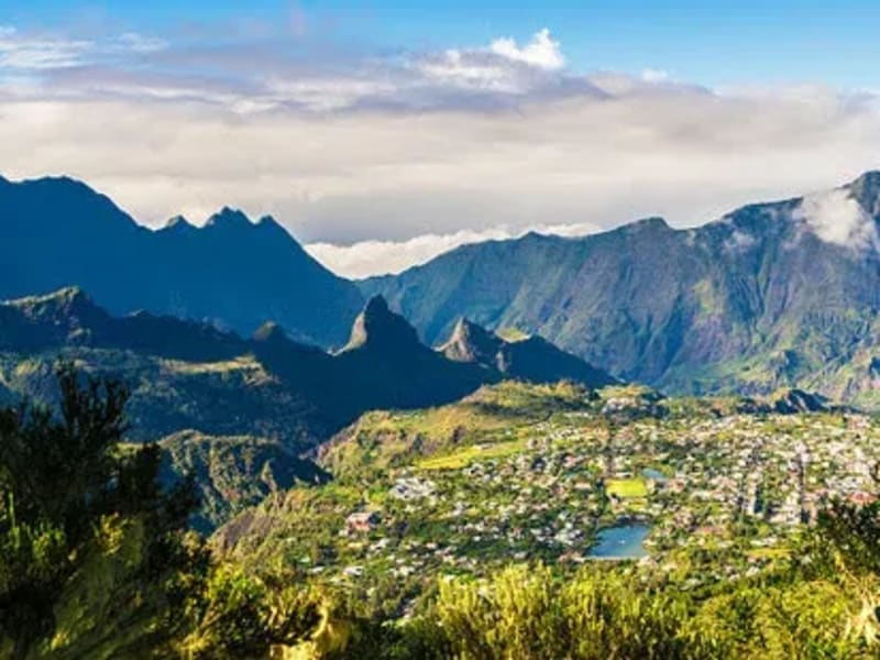 Panorama sur le cirque de Cilaos, village et petit plan d'eau au fond de la cuvette, crêtes découpées sous les nuages