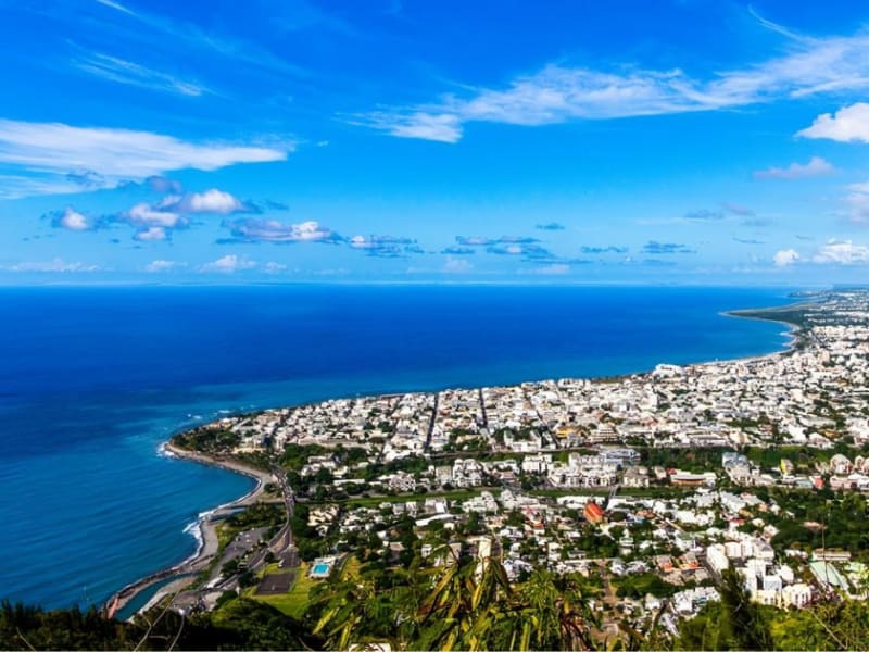 Littoral nord de La Réunion vu des hauteurs, ville blanche étalée jusqu'à l'océan bleu sous un ciel de beau temps