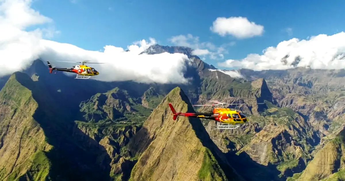 Deux hélicoptères au-dessus du cirque de Mafate à La Réunion, vue aérienne des pitons et de la mer de nuages