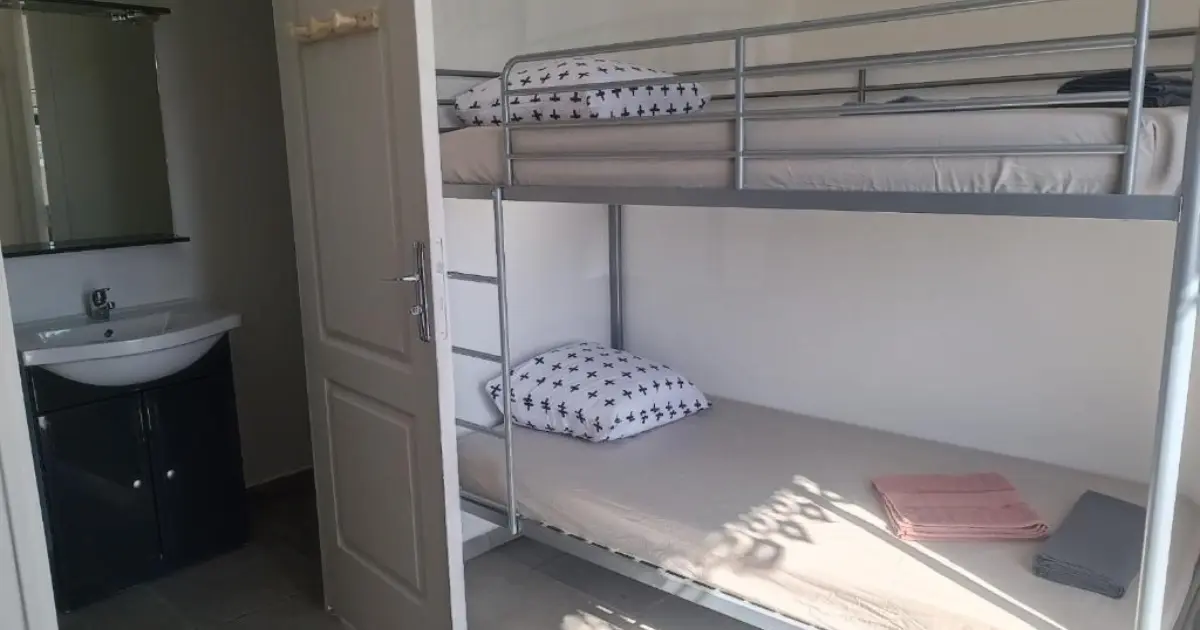 Intérieur du Kazhotel avec lits superposés métalliques du dortoir et lavabo de la salle d'eau attenante