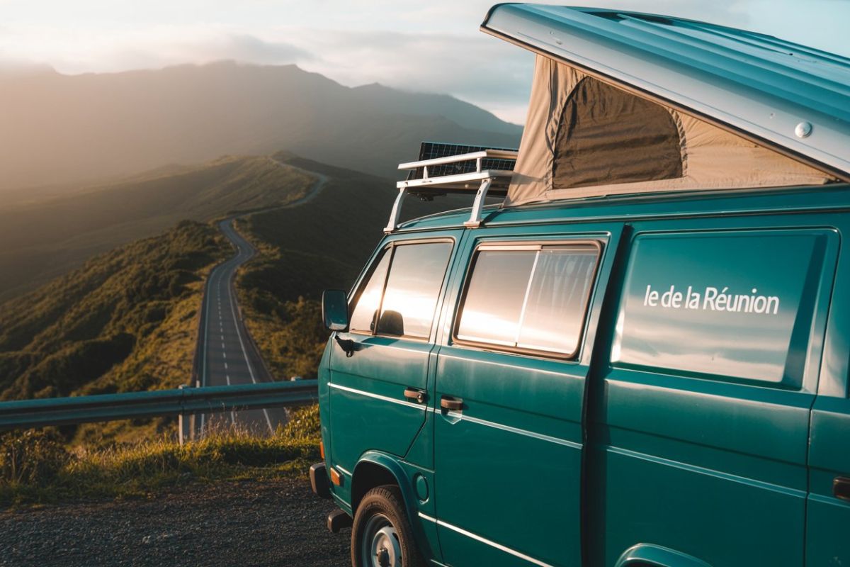 Van VW Combi vert avec toit relevable ouvert et panneaux solaires sur la route forestière du volcan au coucher de soleil, road-trip familial à La Réunion