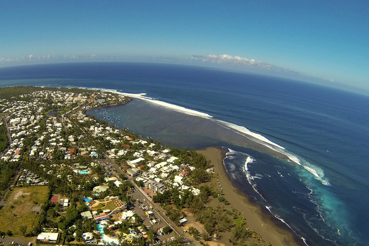 Black sand beach at l'Étang-Salé in Reunion Island with a casuarina forest in the background