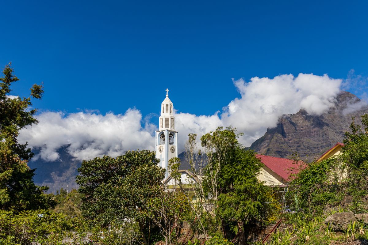 Église Notre-Dame des Neiges de Cilaos, clocher blanc devant les nuages et le rempart, La Réunion