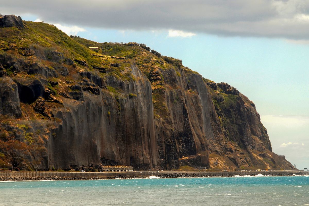 Route du littoral de La Réunion au pied de la falaise basaltique du Cap Bernard, axe iconique du tour de l'île