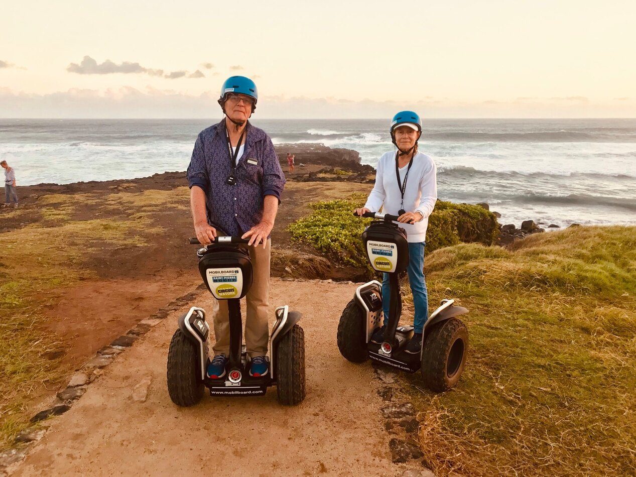 Couple senior en Segway au bord de la côte ouest au coucher de soleil, La Réunion