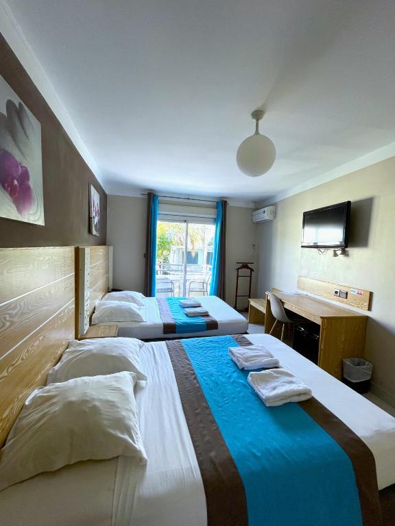 Chambre quadruple de l'Hôtel Select avec 2 lits jumeaux, télévision murale et baie vitrée sur la terrasse