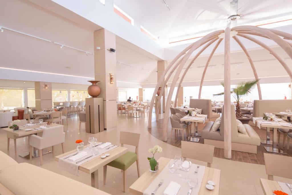 Salle du restaurant Le Dôme de l'Akoya avec sa structure en bois clair, tables dressées et fauteuils élégants