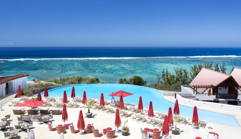 Piscine à débordement de l'Akoya face au lagon de La Saline avec parasols rouges et transats