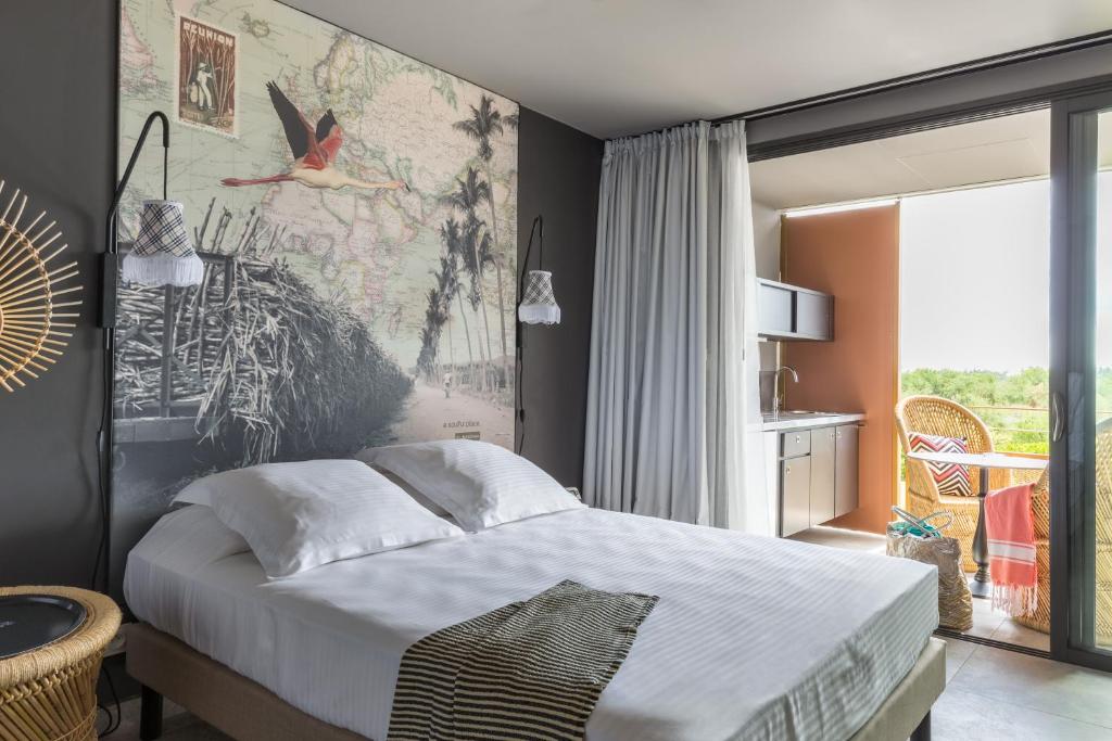 Chambre du Dina Morgabine avec mur tête de lit imprimé carte Réunion et flamant rose, kitchenette et terrasse