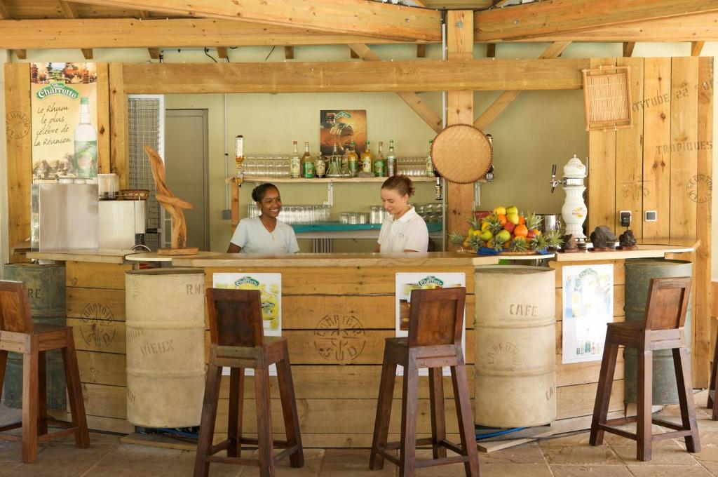 Bar plage de l'Hôtel Le Récif avec comptoir bois, fûts en céramique, bouteilles de rhum Charrette et serveuses créoles