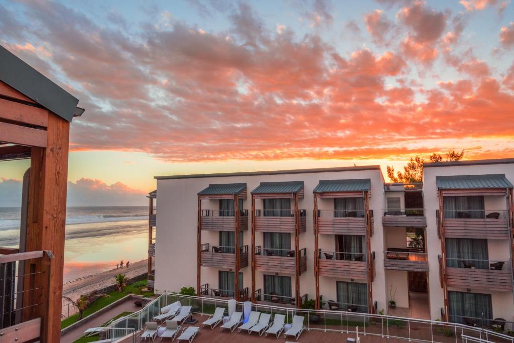 Façade extérieure du Battant des Lames au coucher de soleil avec balcons bois et plage en arrière-plan