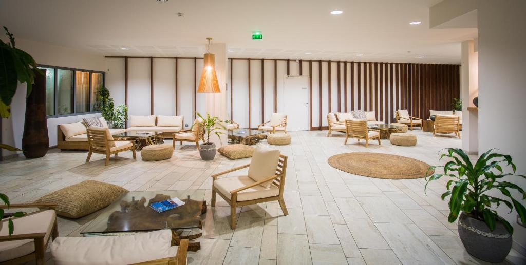 Salon commun du Battant des Lames avec mobilier en rotin, fauteuils blancs et plantes vertes