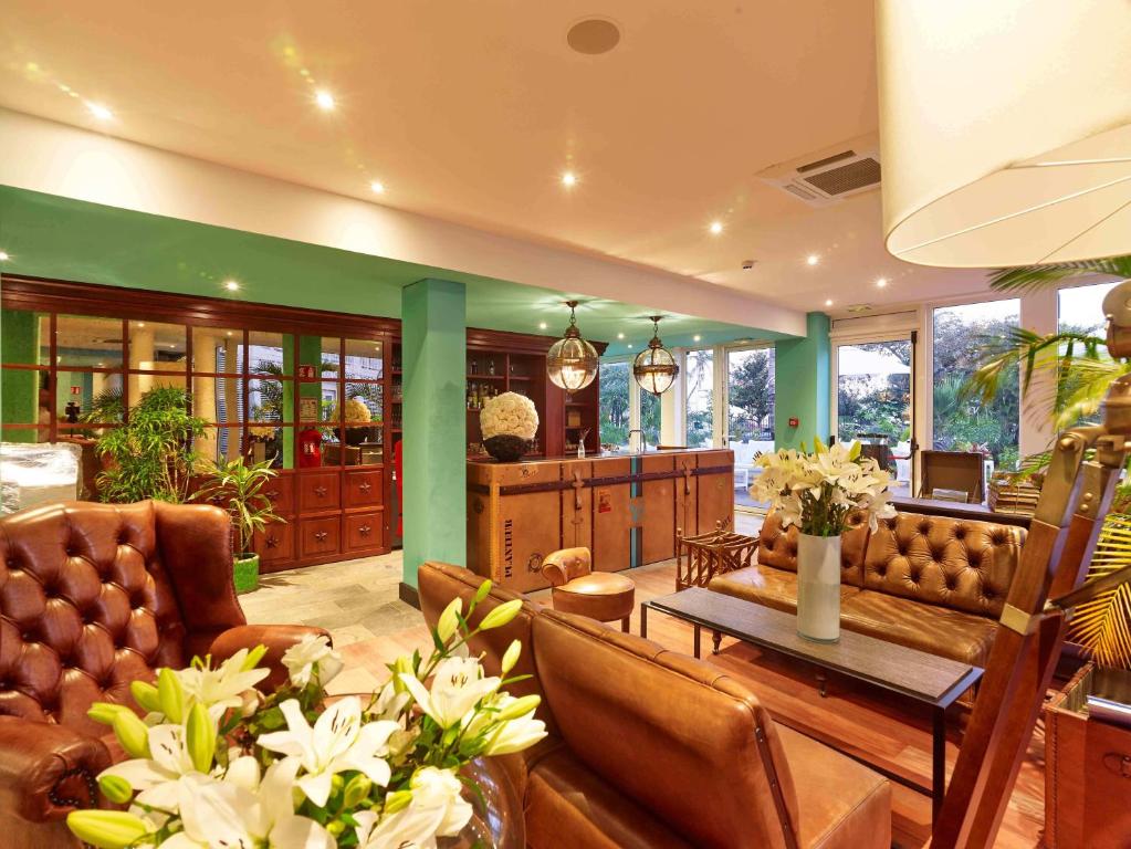 Lobby de la Villa Delisle avec fauteuils Chesterfield en cuir, bar Le Planteur en bois et bouquets de fleurs