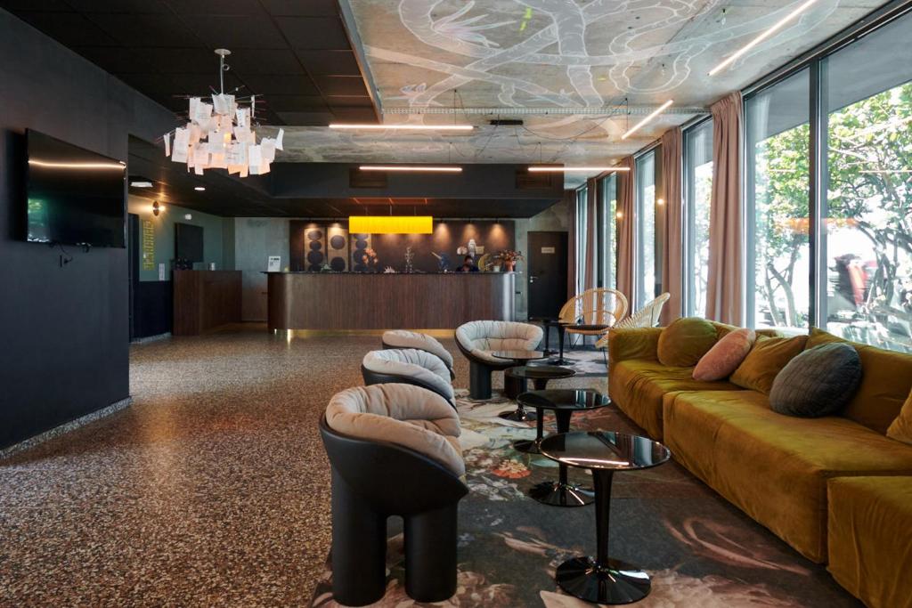 Lobby design du Dina Morgabine avec canapé jaune moutarde, fauteuils contemporains et lustre suspendu