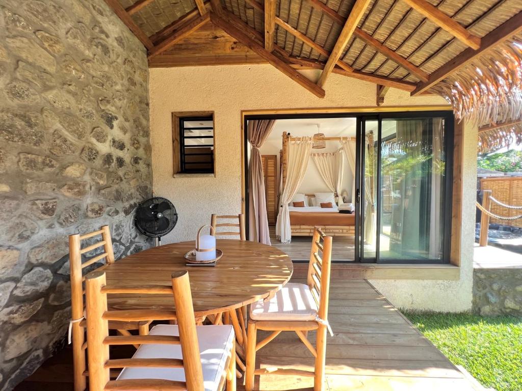 Terrasse en bois des Vavangues avec table, chaises tressées et vue ouverte sur la chambre à baldaquin