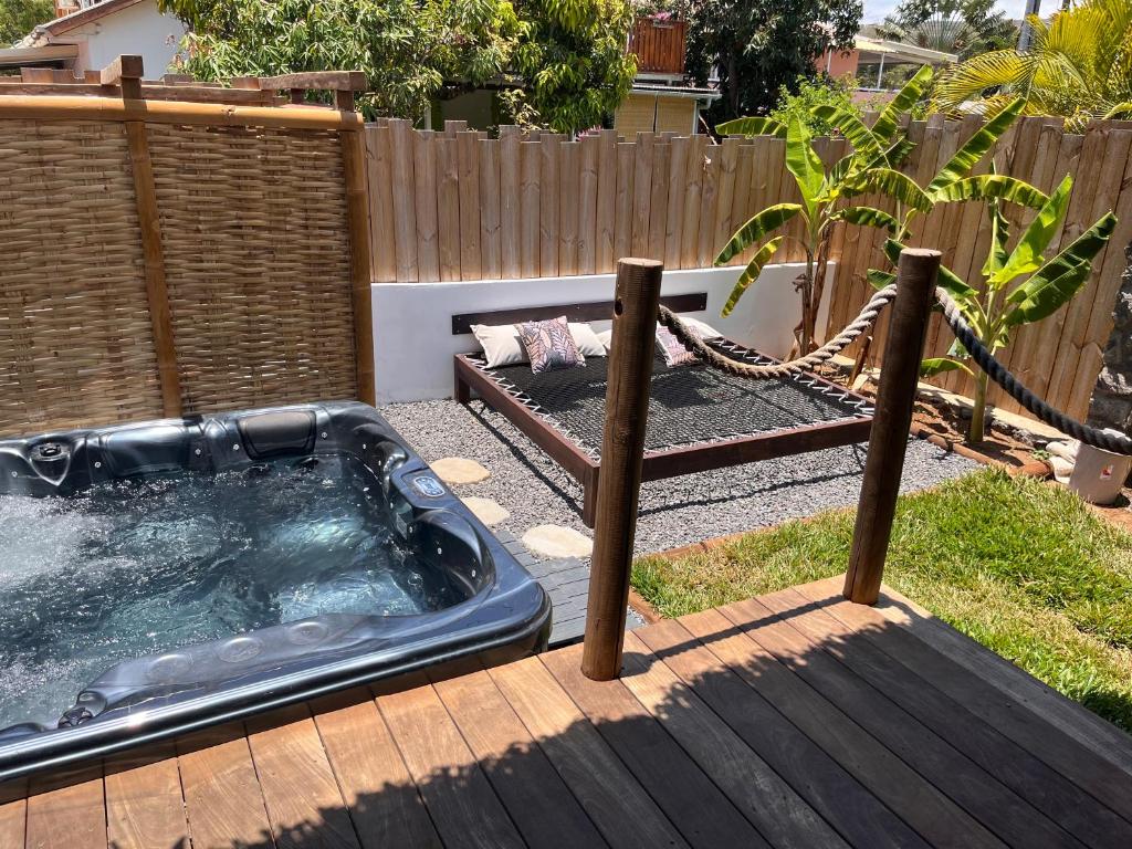 Jacuzzi privatif noir sur terrasse bois des Vavangues, avec lit suspendu et bananiers à l'arrière-plan