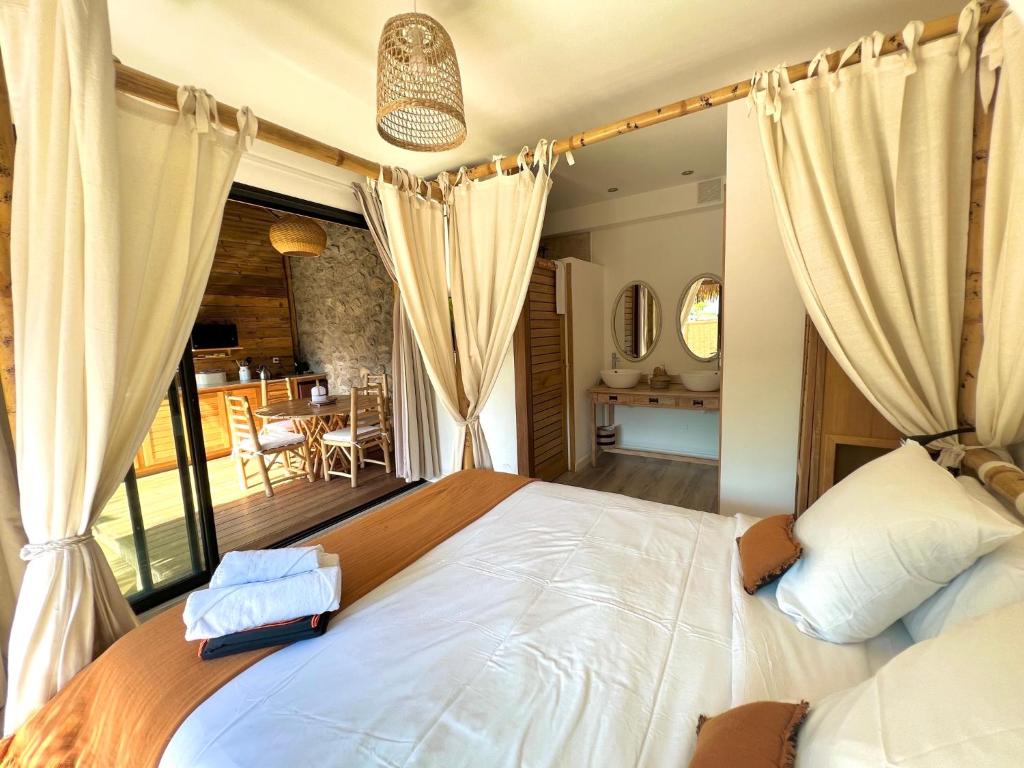 Vue de la chambre des Vavangues avec lit baldaquin ouvert sur la terrasse bois et la salle de bain à double vasque