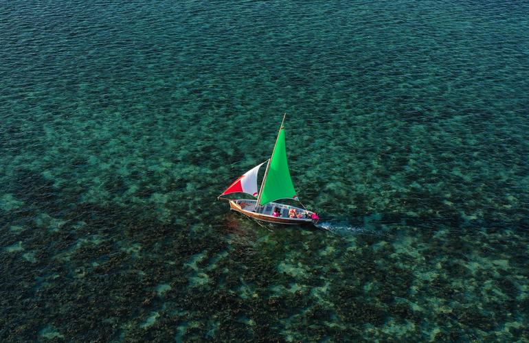 Pirogue traditionnelle à voile verte et rouge sur le lagon turquoise de l'île Maurice