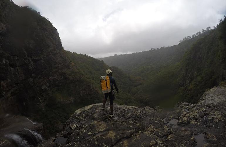 Canyoneur sac jaune fluo en surplomb d'une falaise des gorges de Rivière Noire à l'île Maurice
