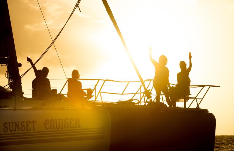 Silhouettes de passagers sur le pont d'un catamaran « Sunset Cruiser » au coucher du soleil à l'île Maurice