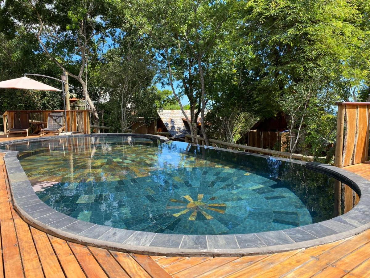 Piscine ovale en mosaïque du Lodge Roche Tamarin nichée dans la forêt tropicale, entourée d'arbres et de terrasses bois