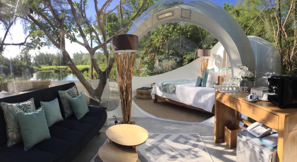 Intérieur d'une bulle transparente Bubble Lodge sur l'île aux Cerfs, lit blanc face au lagon au coucher du soleil