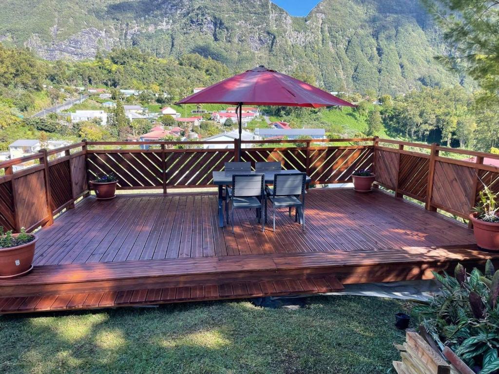 Terrasse panoramique en bois du gîte Le Guétali avec table, parasol rouge et vue sur les remparts du cirque de Salazie