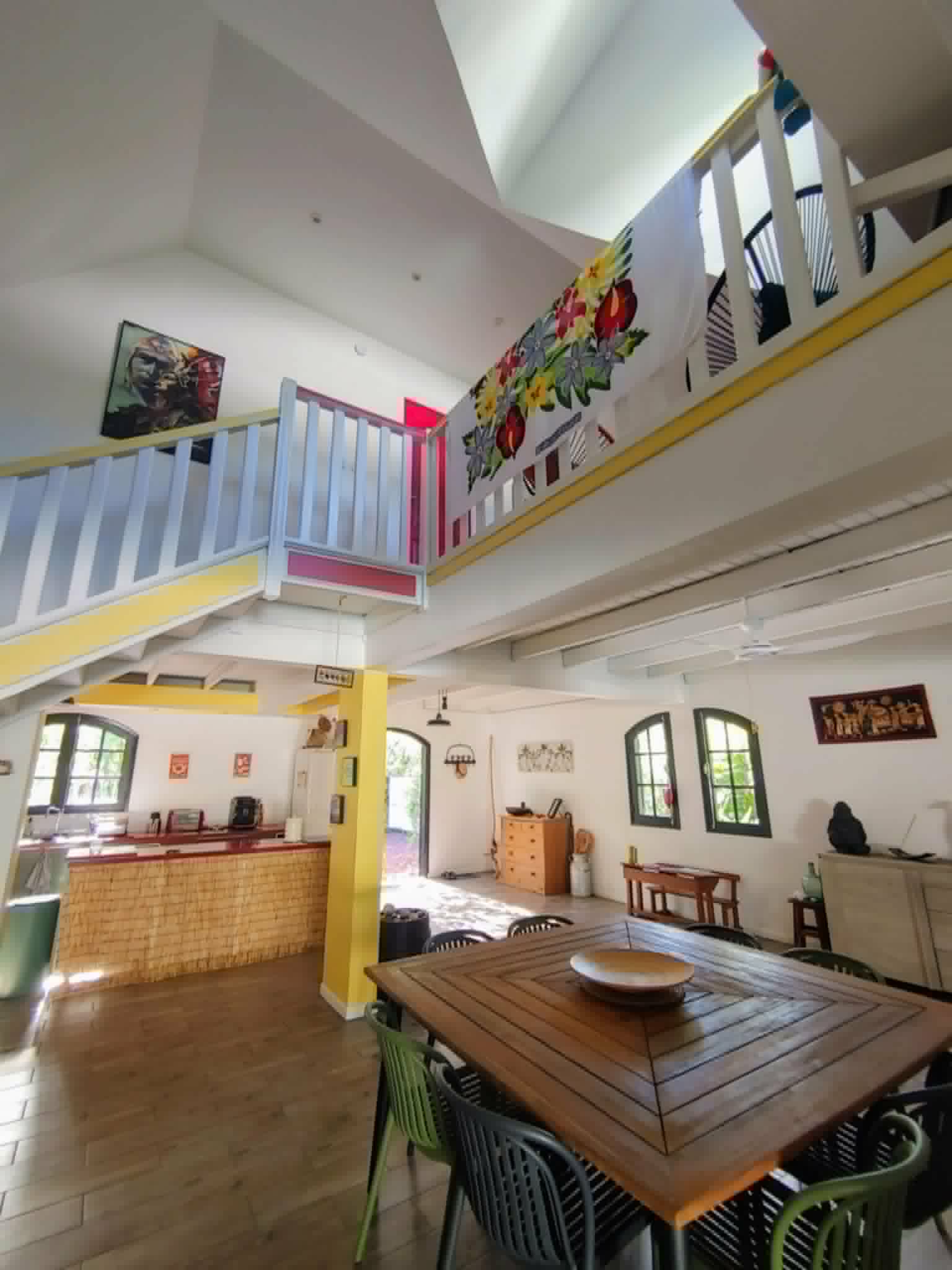 Pièce de vie d'Eskal Péi avec mezzanine, grande table à manger et cuisine ouverte