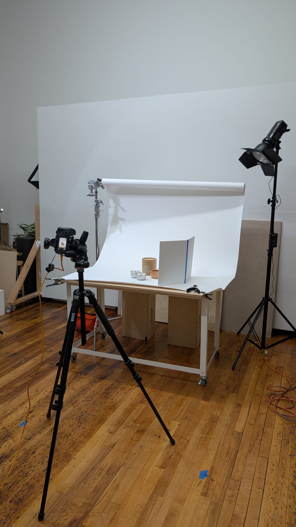 A white paper sweep curving onto a table with a camera on a tripod and a strobe aimed at it