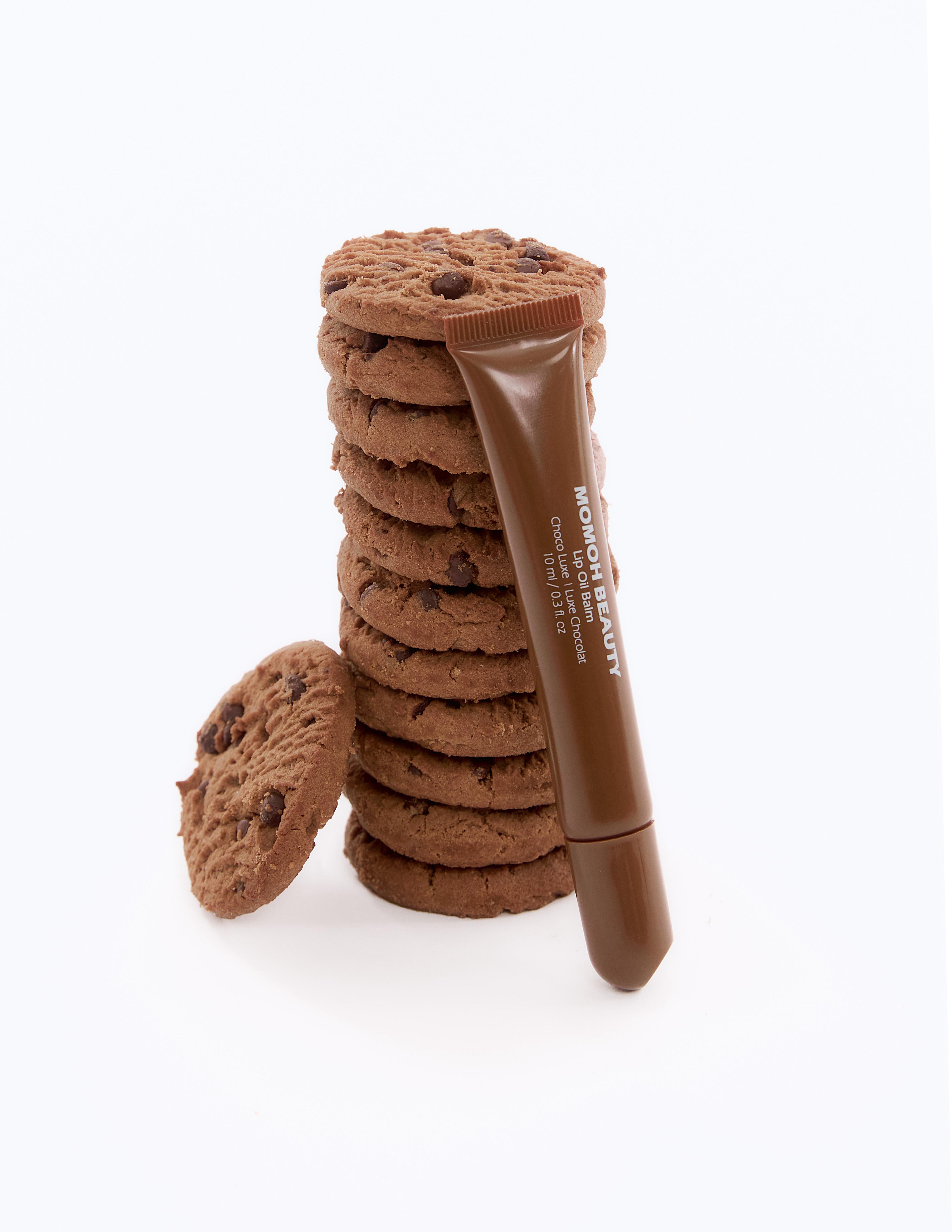 Choco Luxe Lip Oil Leaning on Chocolate Cookies