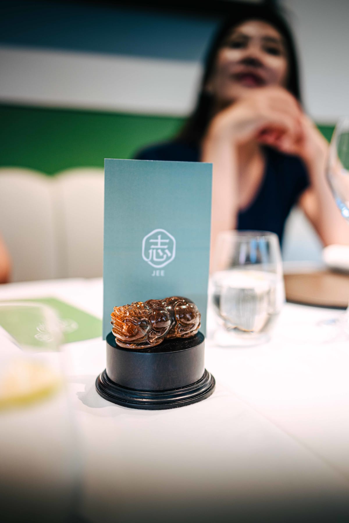 JEE, Hong Kong: a card with the restaurant's name, 志, behind a small carved crystal beast
