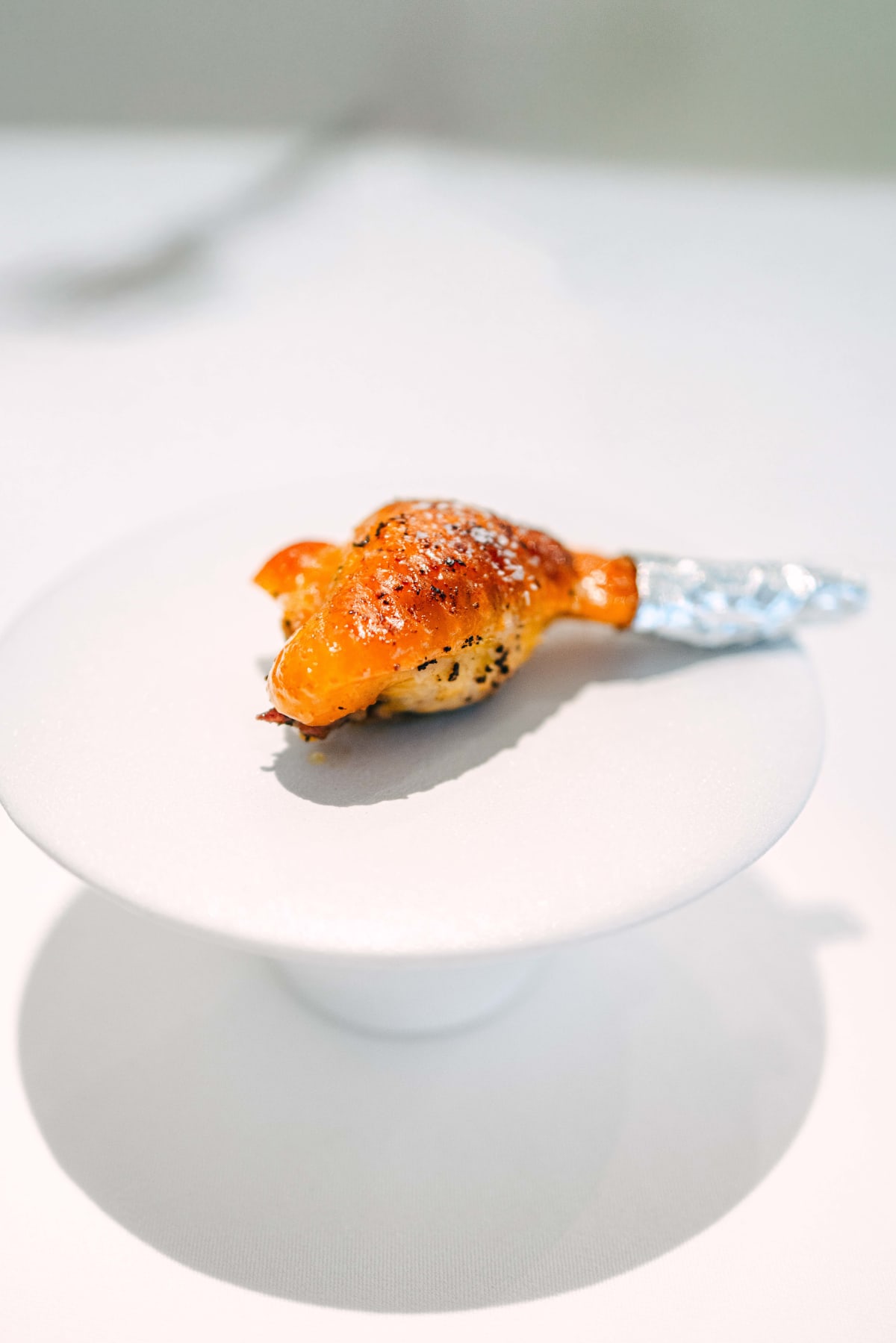 JEE, Hong Kong: the stuffed chicken wing on a raised plate, its bone wrapped in foil