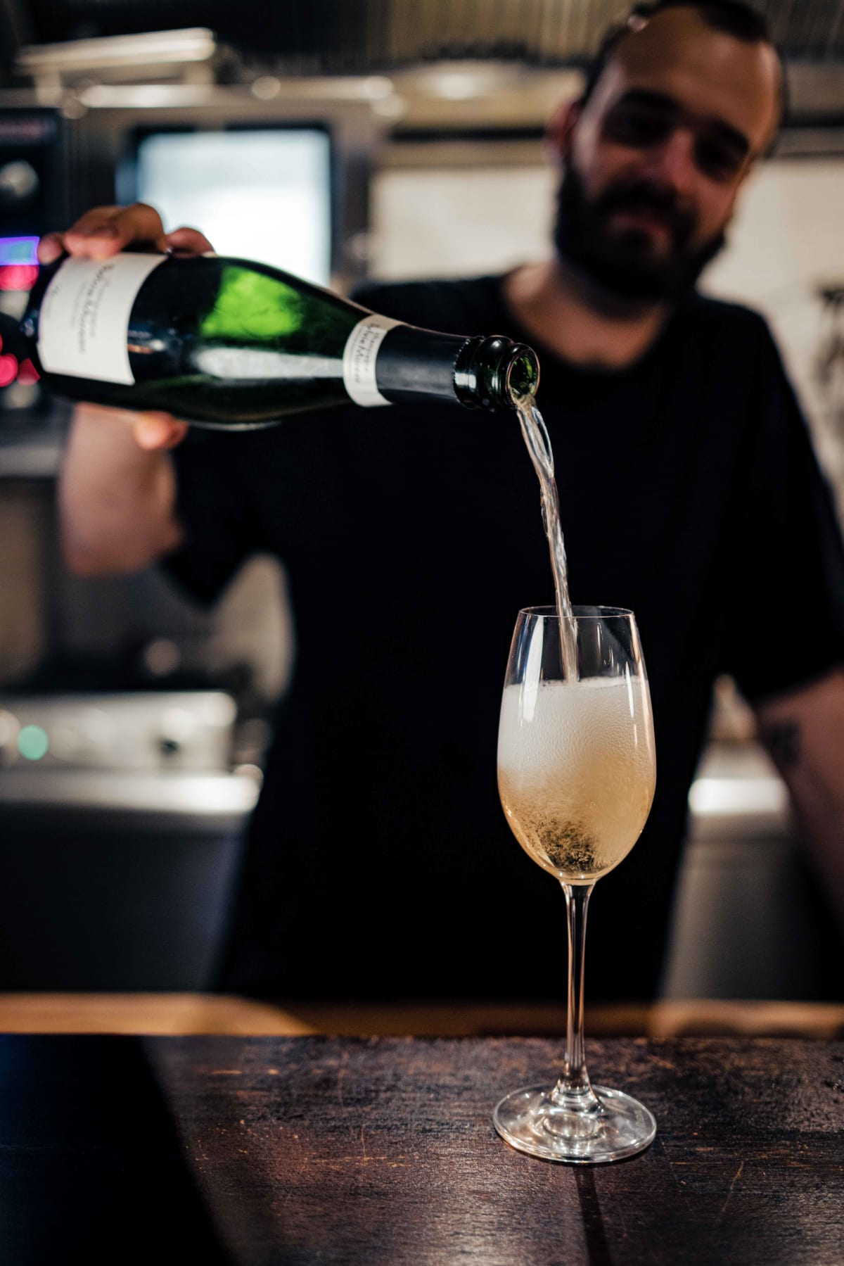 Bistro de la Mer, Amsterdam: a server in a black T-shirt pouring the champagne at the counter