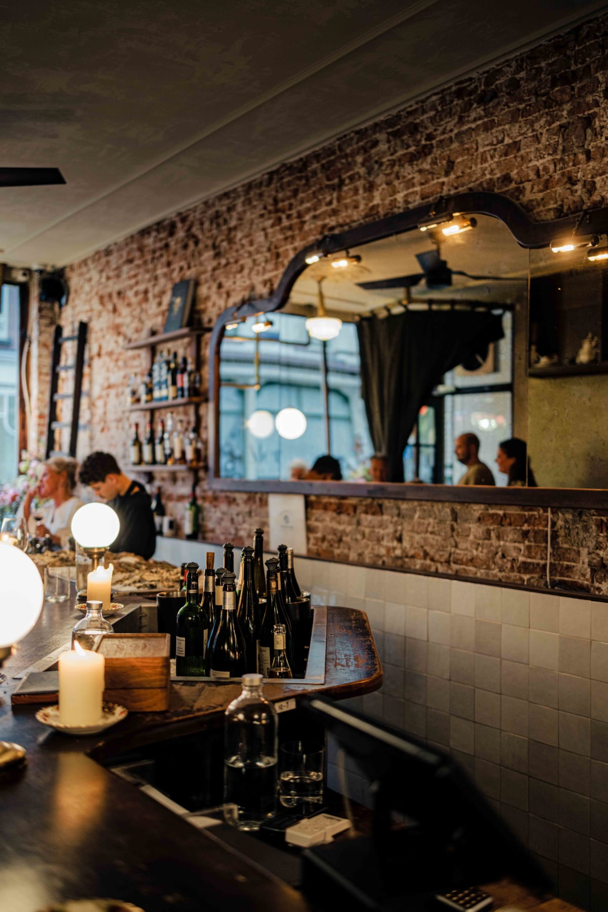 Bistro de la Mer, Amsterdam: the bar, with bottles on ice, a brick wall and a long mirror