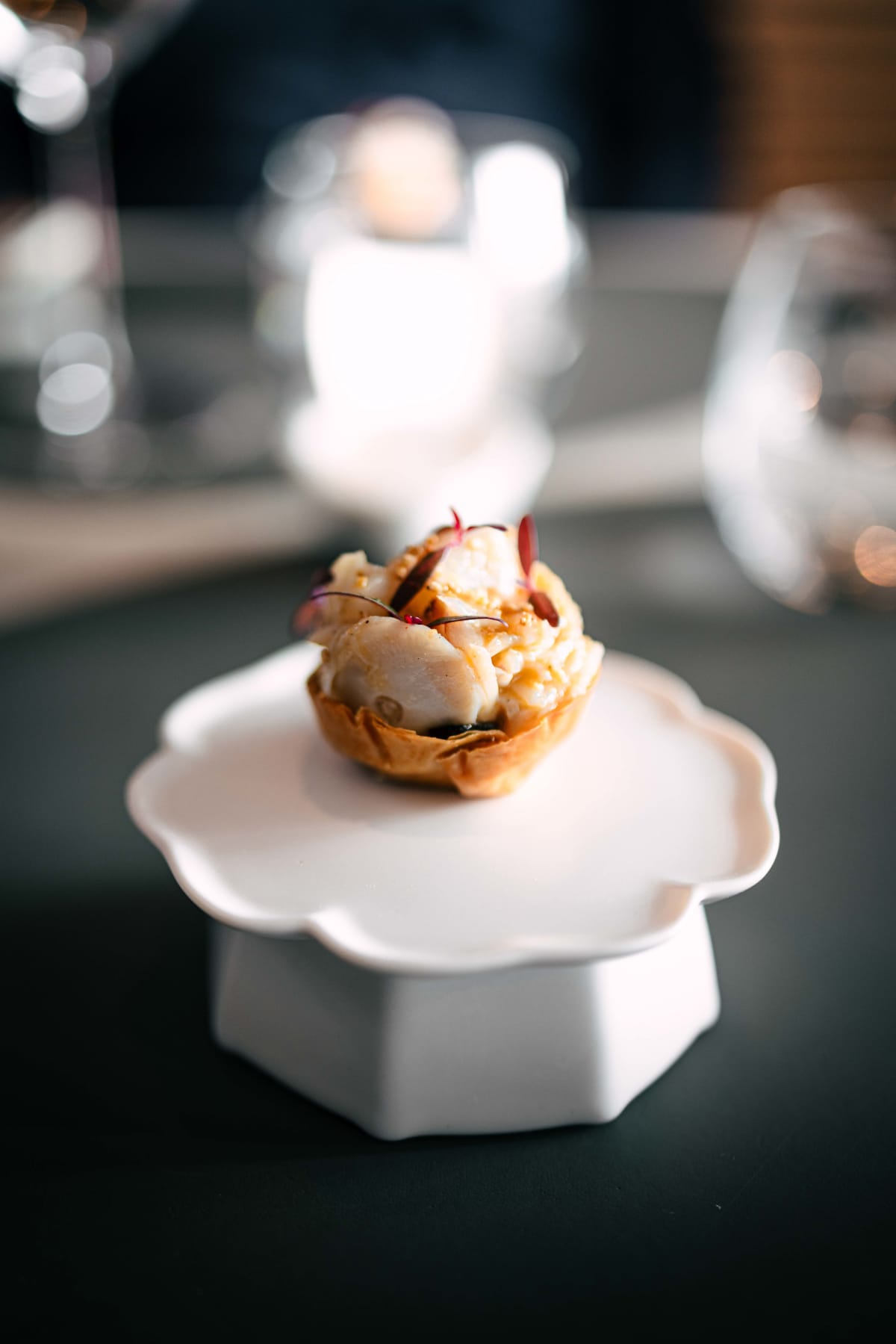 Exquisine, Seoul: the first snack, octopus in a crisp pastry cup on a scalloped white plate raised on a stand