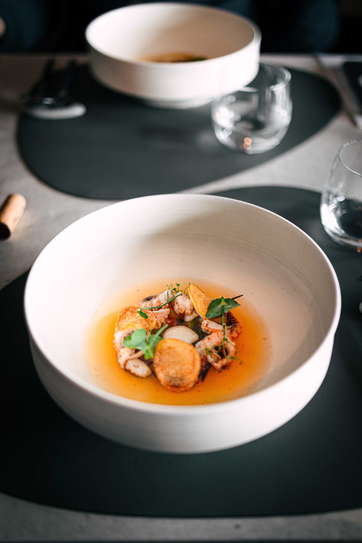 Exquisine, Seoul: the Potato course in its bowl of amber broth, with octopus, crisp potato discs and pea shoots