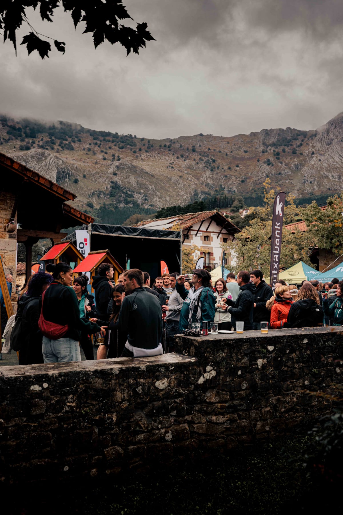 Asador Etxebarri, Axpe: runners and spectators along the stone wall, with the church tower behind