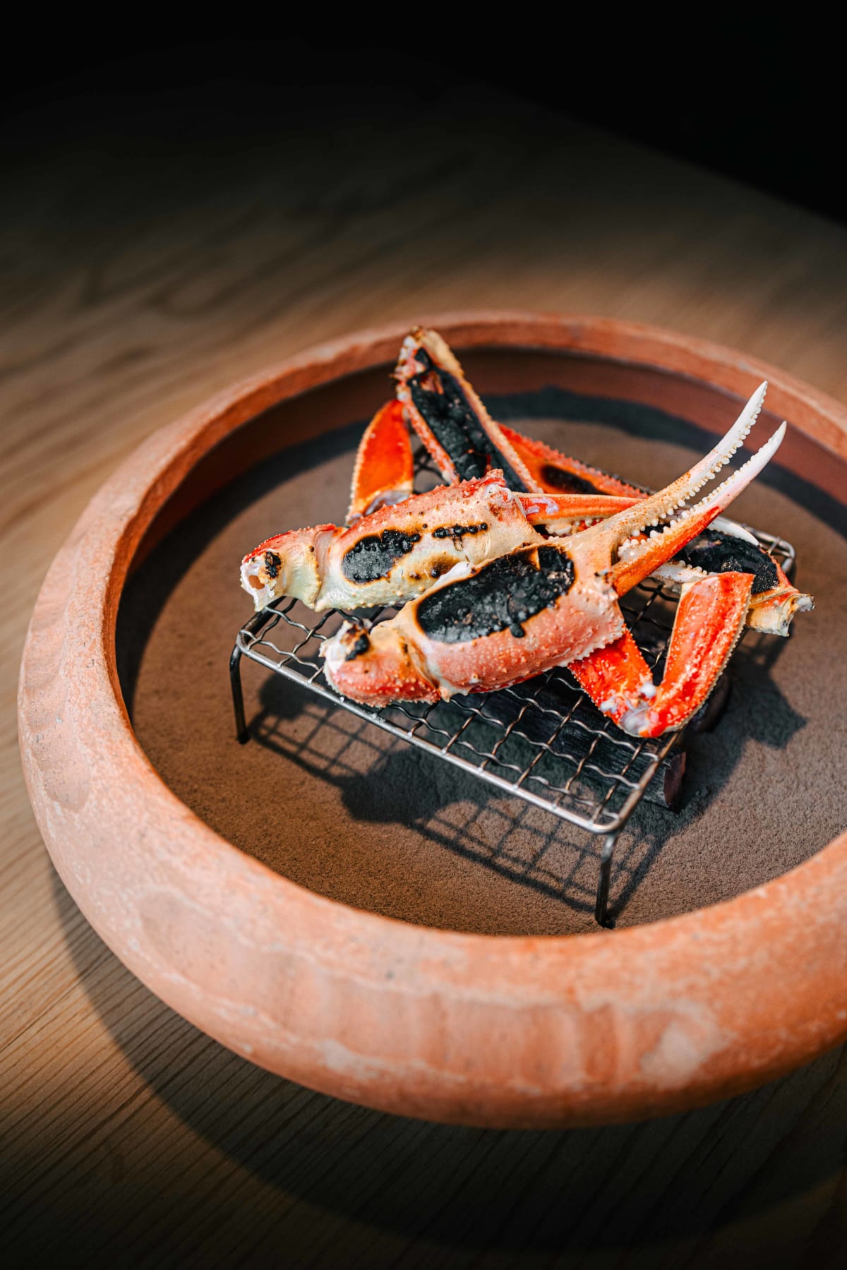 Matsukawa, Tokyo: crab claws and legs grilling on a wire rack over the clay brazier
