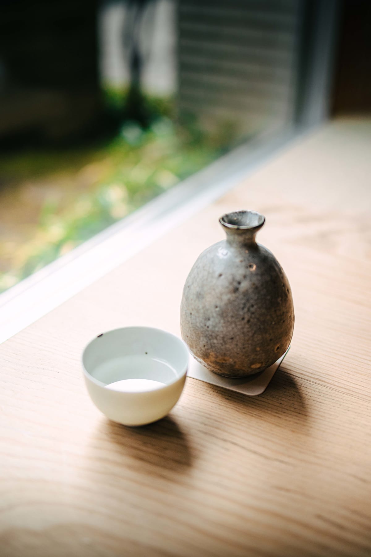 Matsukawa, Tokyo: Kokuryu Shizuku in a grey stoneware tokkuri, a white cup beside it